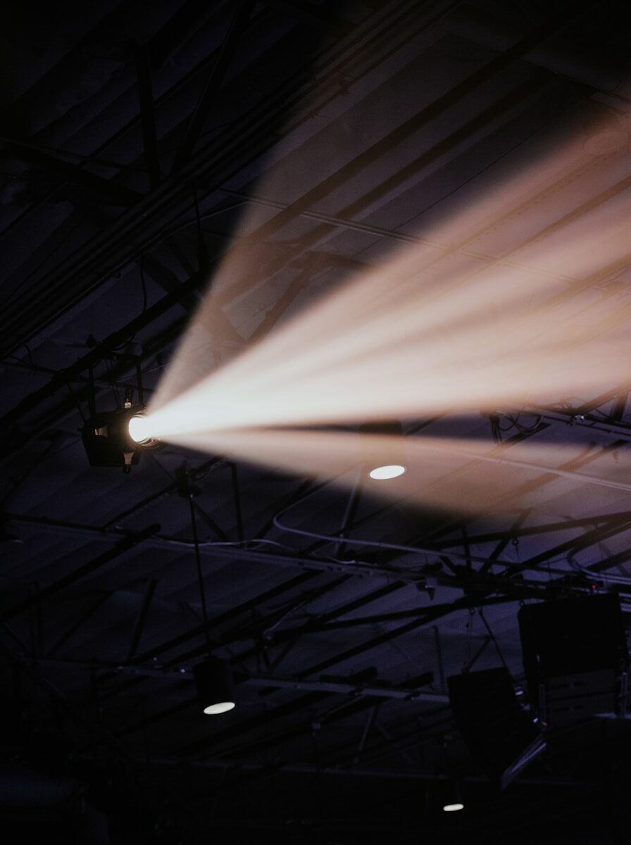 Foco iluminando un escenario oscuro, atmósfera teatral.