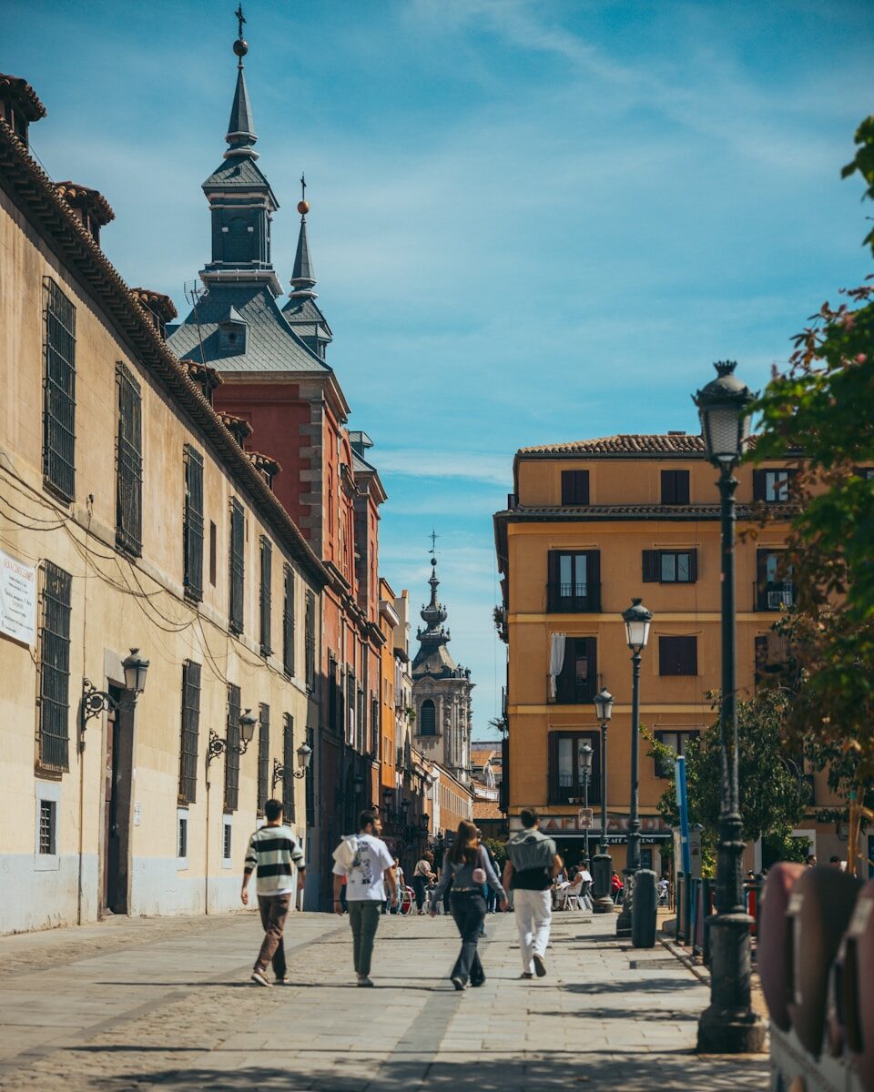 Personas paseando por una calle soleada con edificios históricos en Madrid