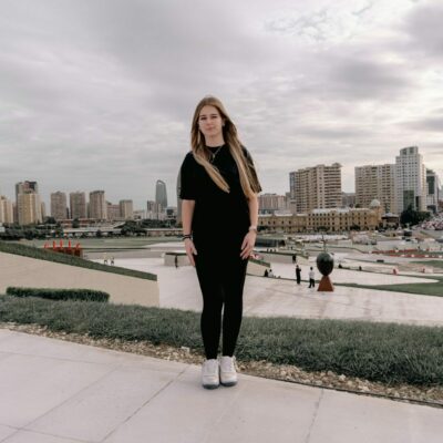 Young woman stands before a city skyline.