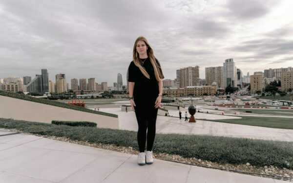 Young woman stands before a city skyline.