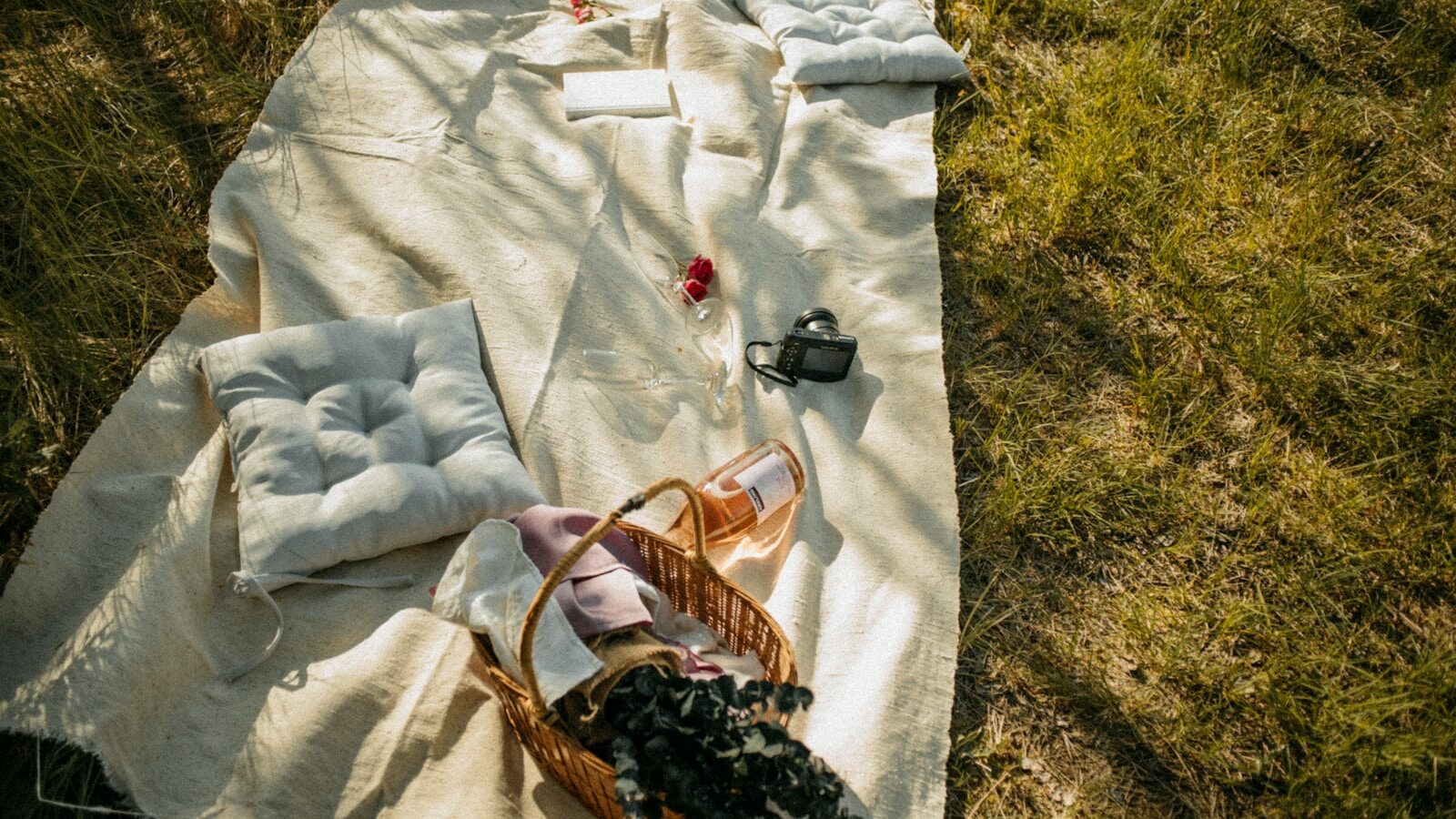 Cesta de picnic y manta con cámara de fotos sobre el césped