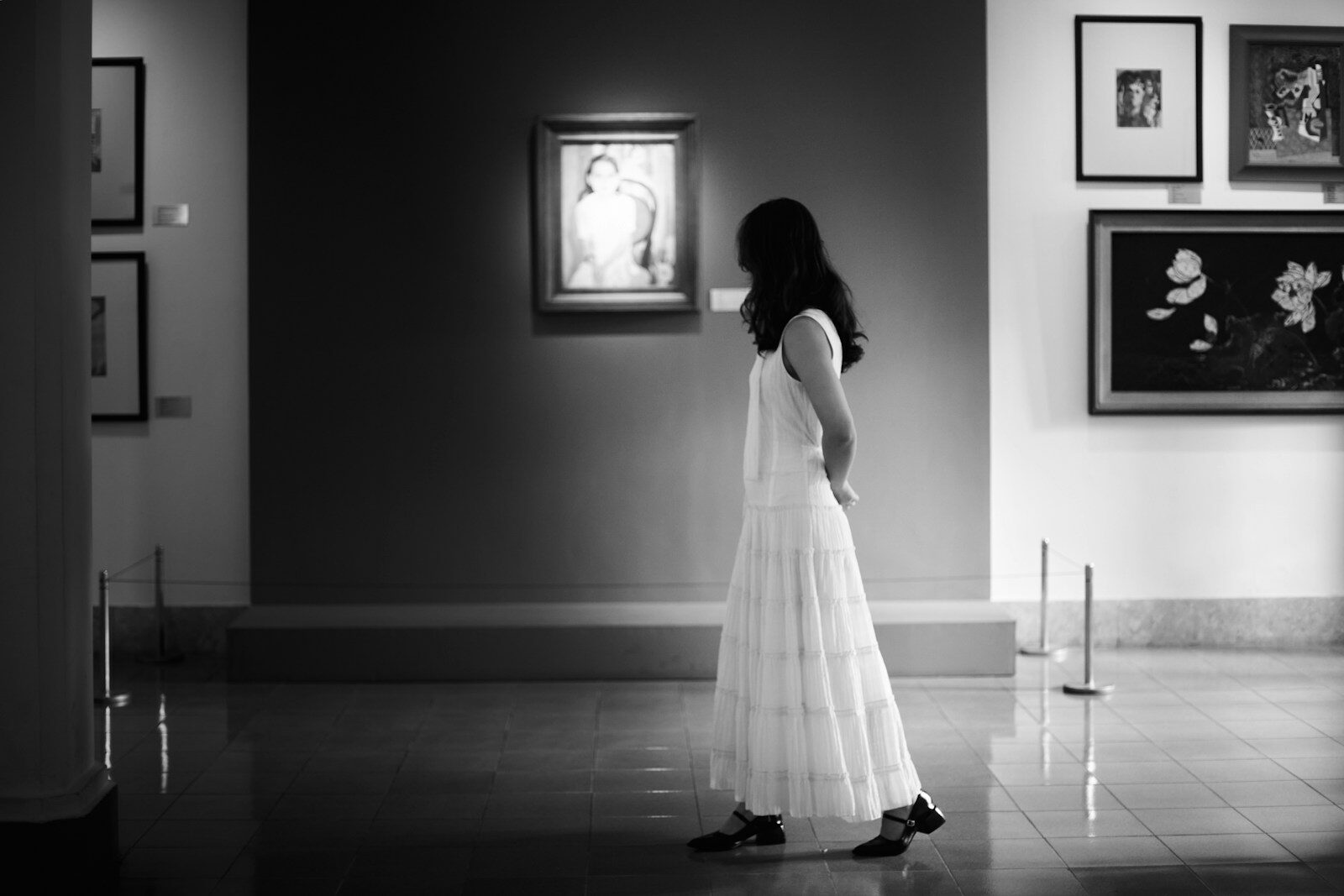 Mujer observando un cuadro en una galería de arte, sola y en silencio
